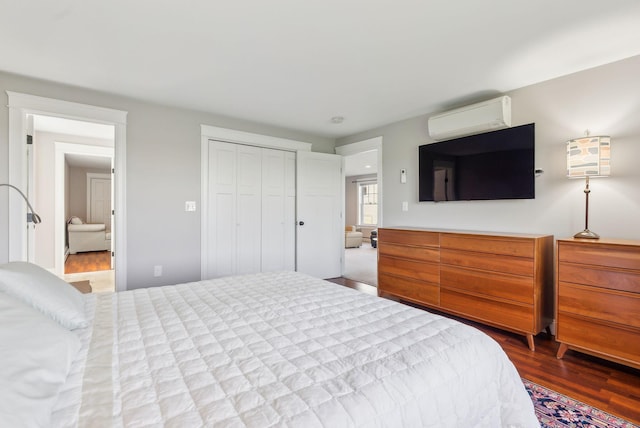 bedroom with an AC wall unit, wood finished floors, and a closet