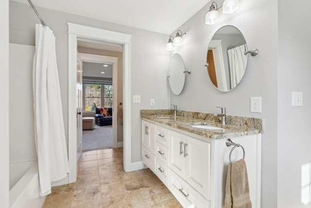 ensuite bathroom featuring double vanity, baseboards, a sink, and ensuite bathroom