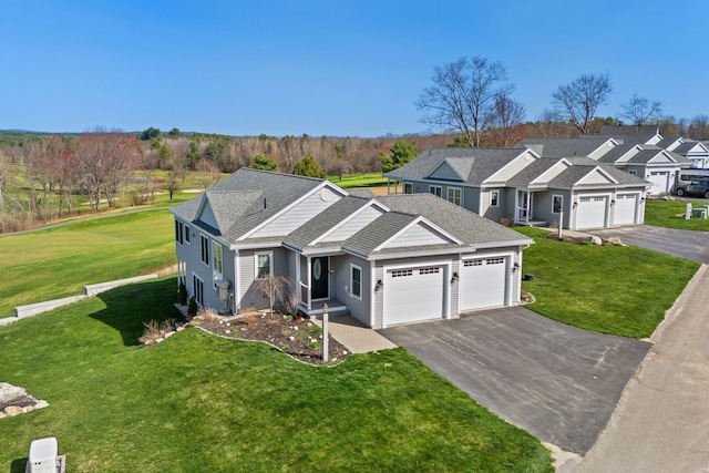 view of front facade with a garage, a front lawn, driveway, and a residential view