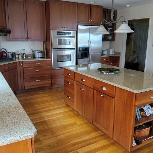 5 Southernpoint Rd, Bristol, ME 04564 - kitchen featuring appliances with stainless steel finishes, light wood-style flooring, under cabinet range hood, light stone countertops, and brown cabinets