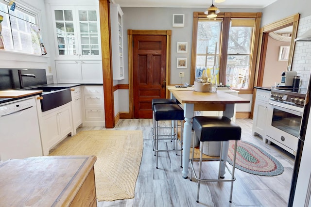 14 Water St, Vinalhaven, ME 04863 - kitchen featuring high end stainless steel range, ornamental molding, a sink, white dishwasher, and white cabinetry