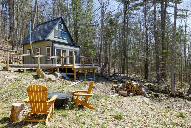 1 Good Day Dr, South Bristol, ME 04568 - back of property with a forest view, a deck, an outdoor fire pit, and metal roof