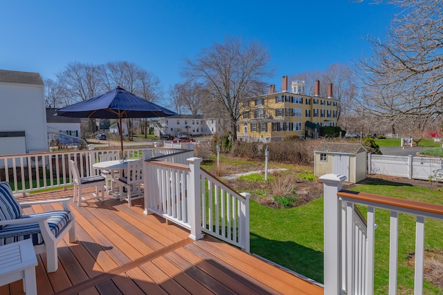 deck featuring a lawn, a storage unit, and an outbuilding