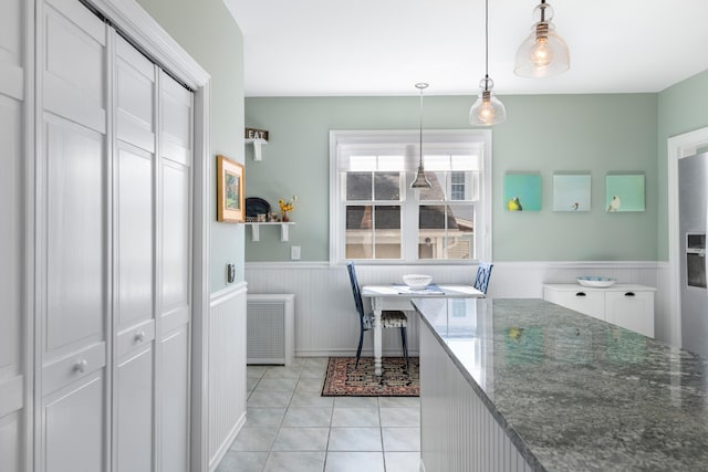 laundry room featuring light tile patterned flooring, radiator heating unit, and a wainscoted wall