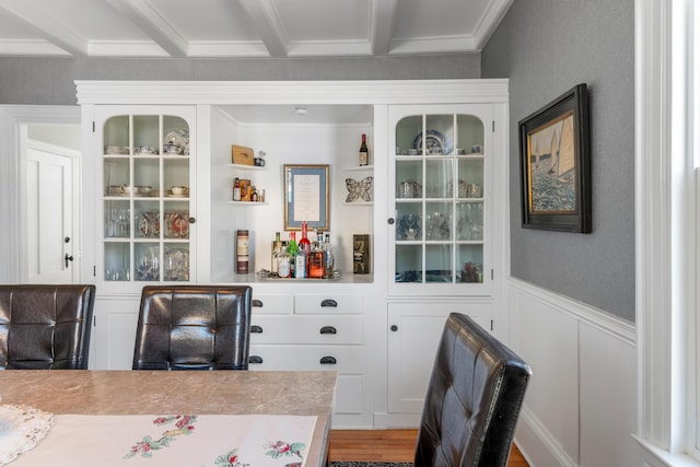 bar with wood finished floors, crown molding, and wainscoting