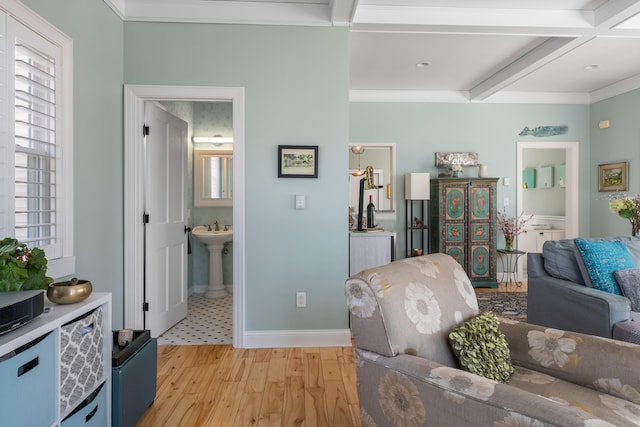 living area with light wood-style floors, a wealth of natural light, beam ceiling, and ornamental molding