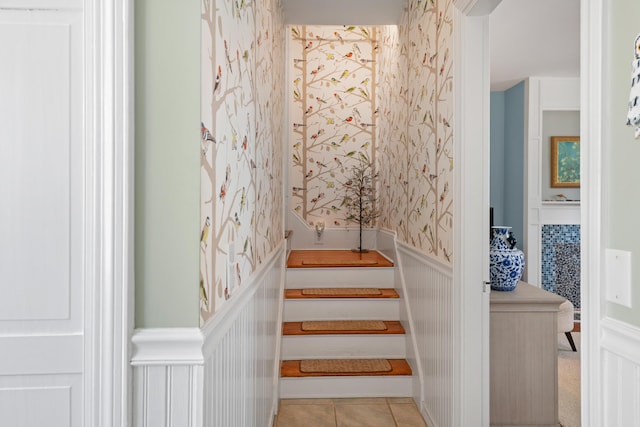 stairway with wallpapered walls, a wainscoted wall, and tile patterned floors