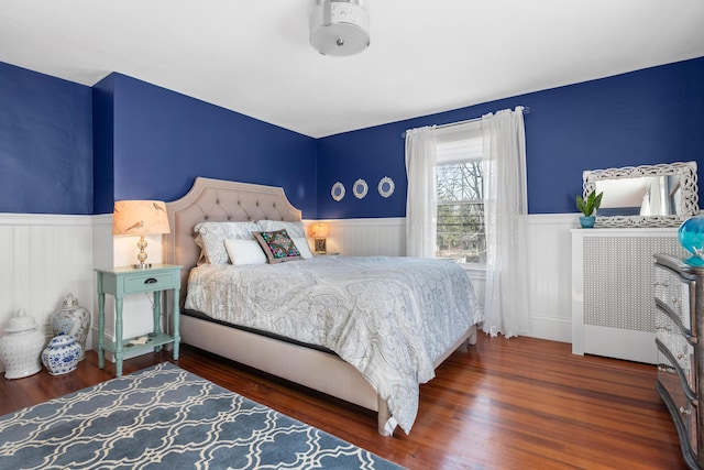 bedroom featuring a wainscoted wall and wood finished floors