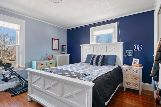 bedroom featuring crown molding, baseboards, wood finished floors, and multiple windows