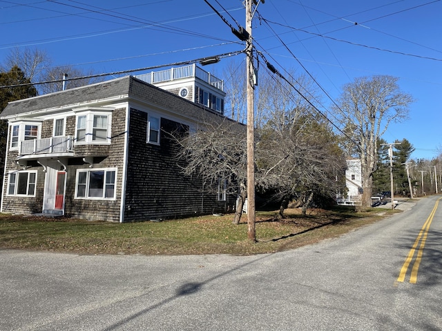 view of side of home with a balcony and a shingled roof