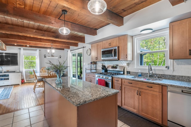 kitchen with appliances with stainless steel finishes, a sink, wood ceiling, light stone countertops, and a center island