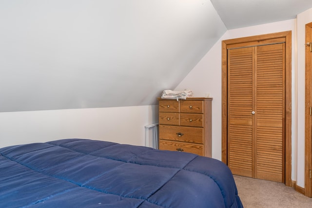bedroom with carpet flooring, lofted ceiling, a closet, and baseboards