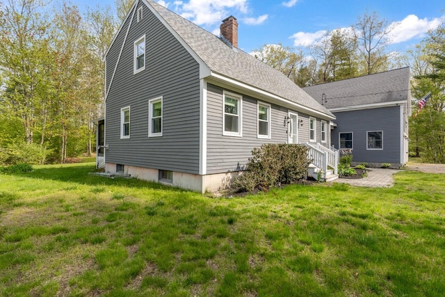 view of side of property with a chimney, a yard, and a shingled roof