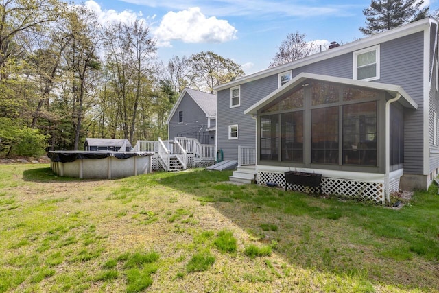 back of house with a sunroom, a covered pool, a wooden deck, and a lawn