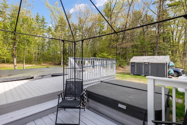 wooden terrace with a storage unit, an outdoor structure, and a hot tub