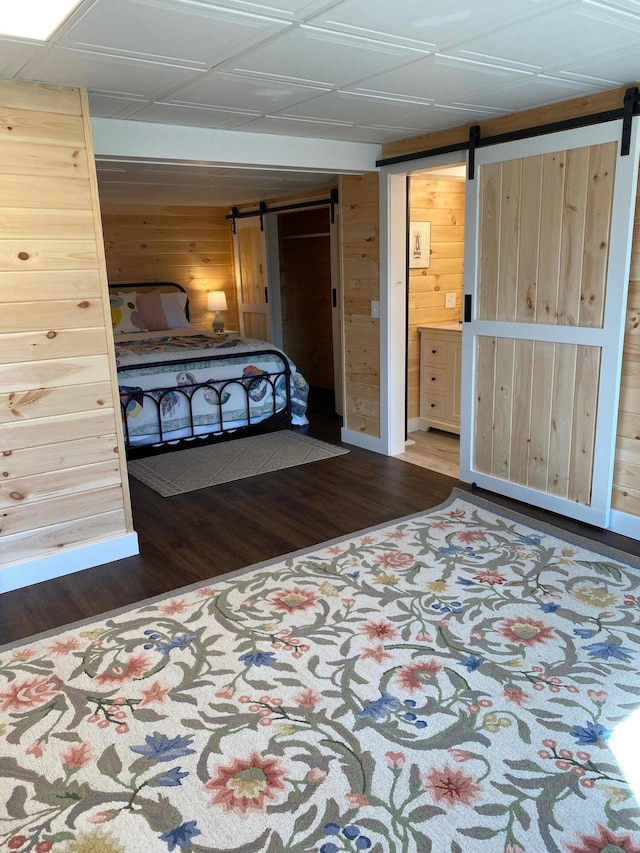18 Pleasant St, Newcastle, ME 04553 - bedroom with a barn door, wooden walls, wood finished floors, baseboards, and connected bathroom