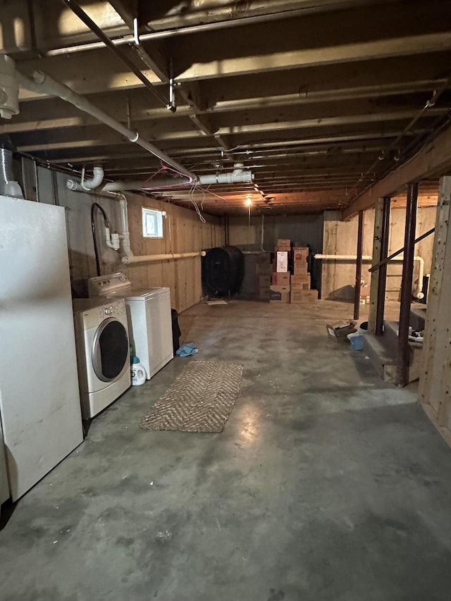 below grade area featuring freestanding refrigerator, washing machine and clothes dryer, and heating fuel