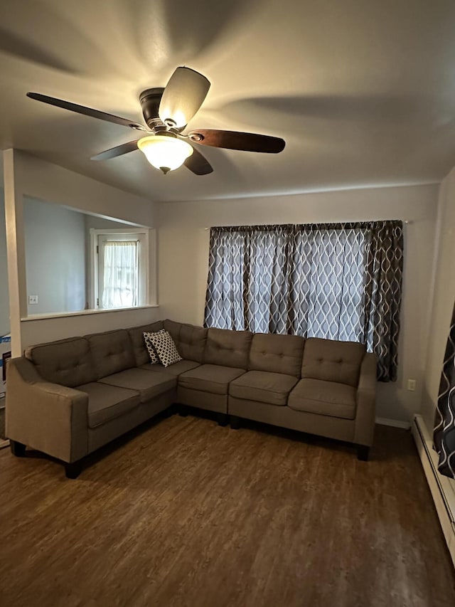 living room featuring a ceiling fan, baseboard heating, and dark wood-style floors