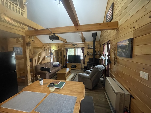 living room with a wood stove, wood walls, beam ceiling, a high ceiling, and stairs