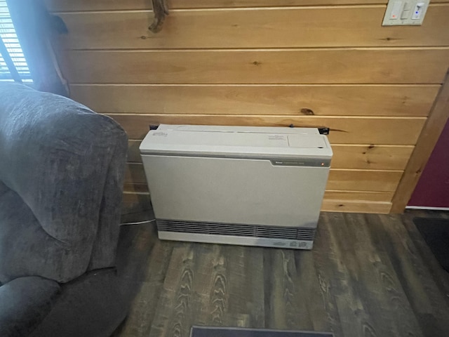 room details featuring heating unit, wood walls, and wood finished floors
