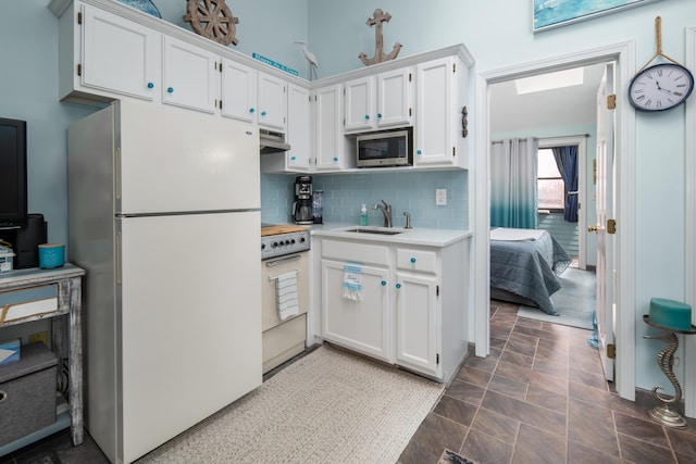 kitchen with a sink, stainless steel microwave, electric range, freestanding refrigerator, and light countertops
