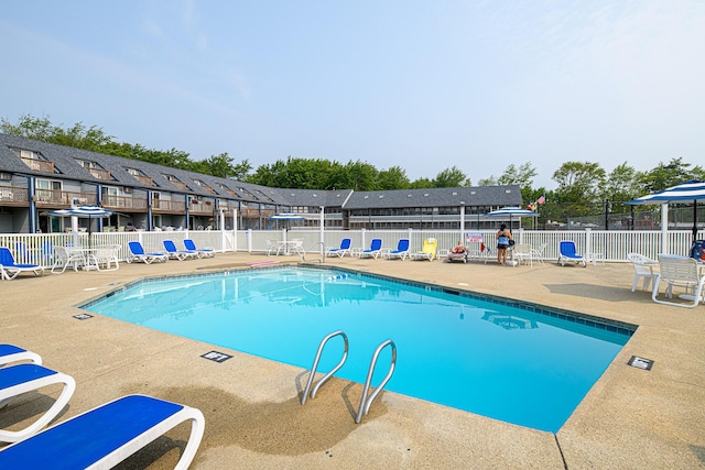 community pool with fence and a patio area