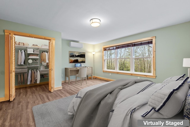 52 Birch Ests, Rome, ME 04963 - bedroom featuring a wall mounted AC, wood finished floors, a closet, baseboards, and a walk in closet