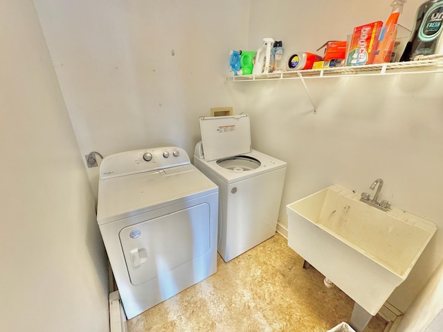 clothes washing area with washer and clothes dryer, laundry area, and a sink