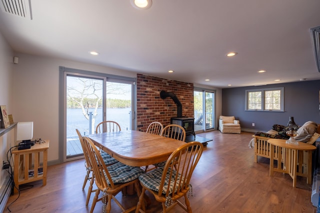 dining room featuring visible vents, a wood stove, baseboards, light wood-style floors, and recessed lighting