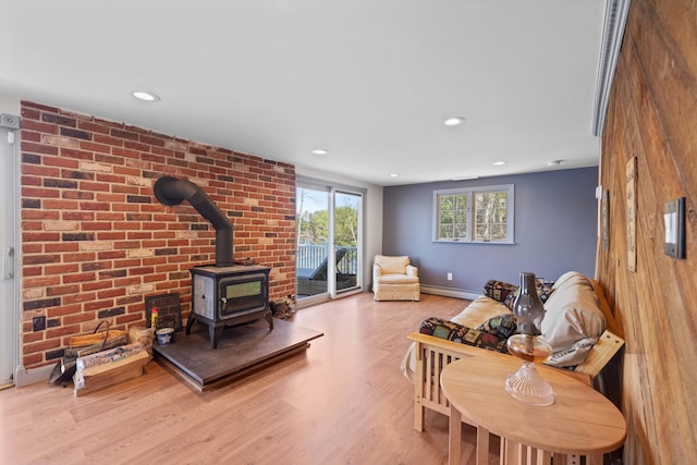 living room with recessed lighting, a baseboard heating unit, wood finished floors, and a wood stove