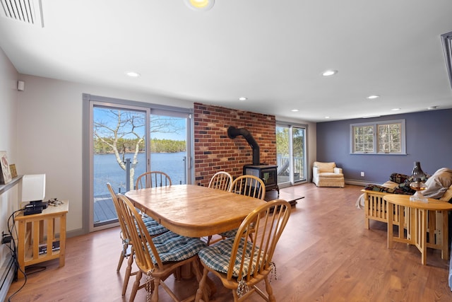 dining space featuring baseboards, a wood stove, recessed lighting, and light wood-style flooring