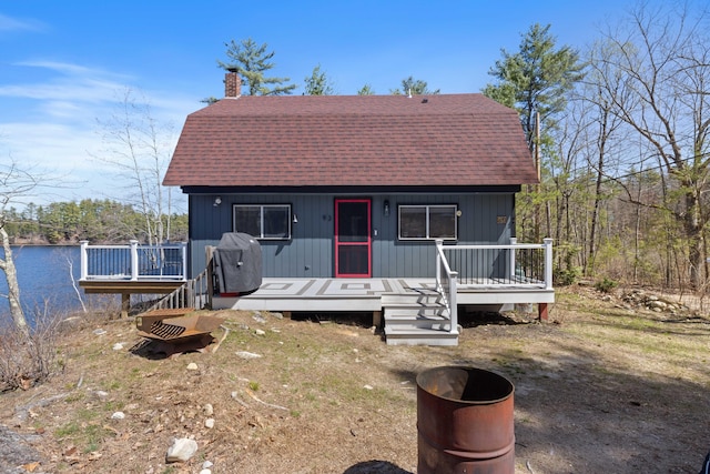 view of front facade featuring a water view, a chimney, and roof with shingles
