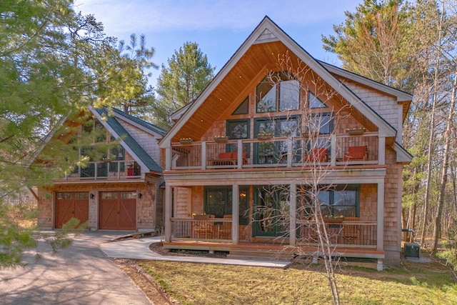 exterior space with covered porch, a balcony, driveway, and an attached garage