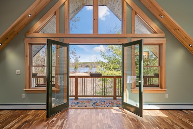 doorway with a healthy amount of sunlight, wood finished floors, a baseboard heating unit, and vaulted ceiling