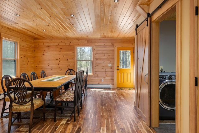 dining space featuring washer / clothes dryer, a barn door, baseboard heating, wooden ceiling, and wood finished floors