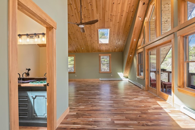 unfurnished living room with wooden ceiling, baseboard heating, wood finished floors, and plenty of natural light