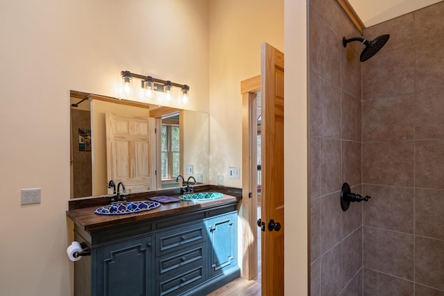 full bath featuring double vanity, a tile shower, and a sink