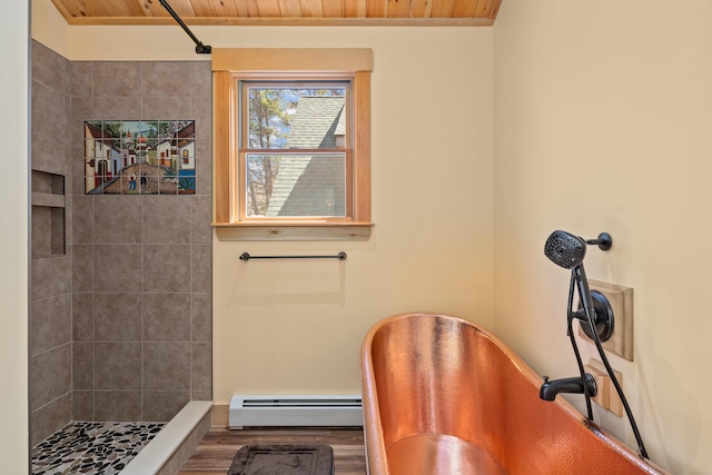 bathroom featuring wood finished floors, a bath, a baseboard heating unit, and tiled shower