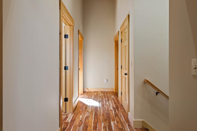 hall with light wood-style flooring and baseboards