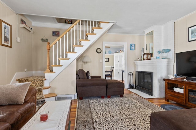 15 Longwood Ave, Old Orchard Beach, ME 04064 - living room with crown molding, a glass covered fireplace, stairs, wood finished floors, and visible vents