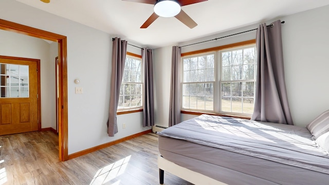 bedroom featuring light wood-style floors, baseboards, and baseboard heating