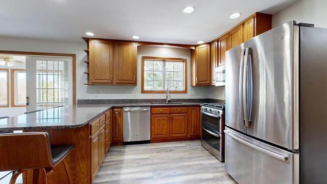 kitchen featuring brown cabinetry, open shelves, a sink, stainless steel appliances, and recessed lighting