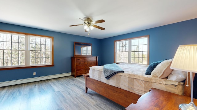 bedroom featuring baseboards, ceiling fan, wood finished floors, and baseboard heating
