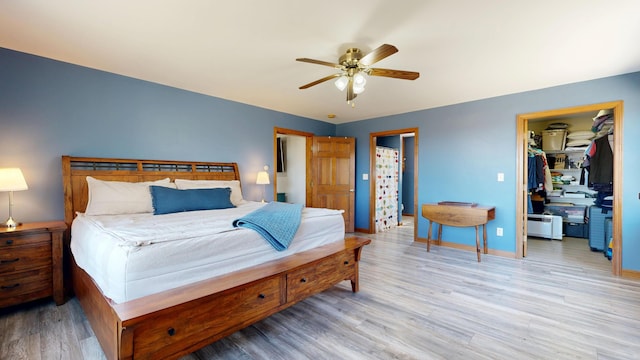 bedroom with light wood-style floors, a ceiling fan, baseboards, a spacious closet, and a closet