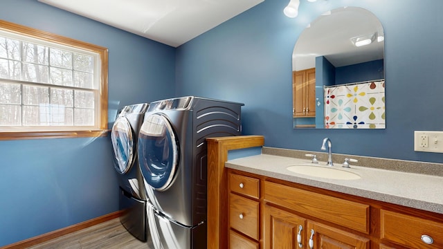 laundry area featuring laundry area, washing machine and dryer, light wood-style floors, baseboards, and a sink
