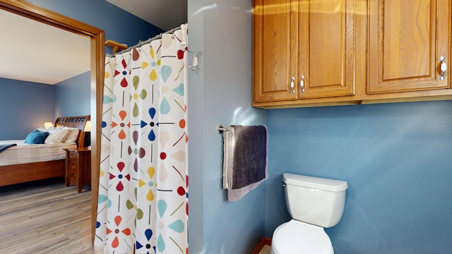 bathroom with ensuite bathroom, wood finished floors, toilet, and curtained shower