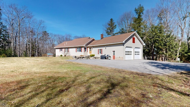 view of front of home with a chimney, a front lawn, and aphalt driveway