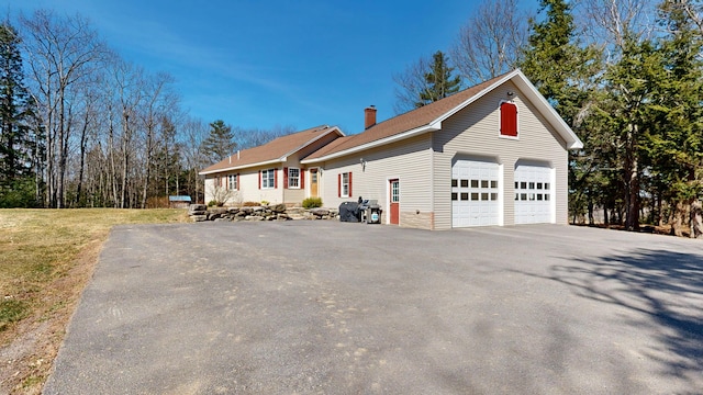 view of front of property with a chimney, an attached garage, and driveway