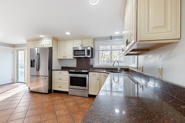 kitchen featuring a sink, cream cabinets, stainless steel appliances, backsplash, and recessed lighting