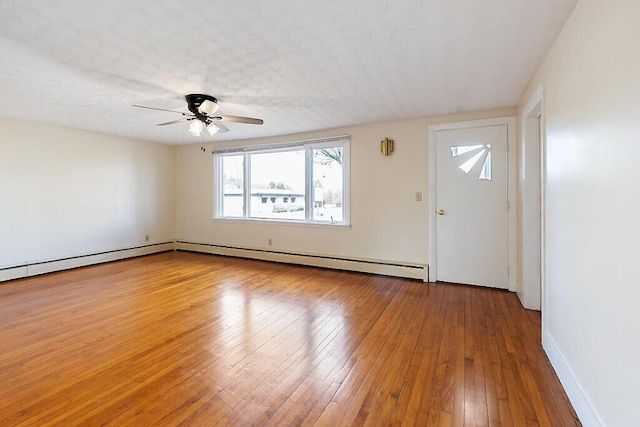 interior space with baseboard heating, baseboards, ceiling fan, and wood-type flooring